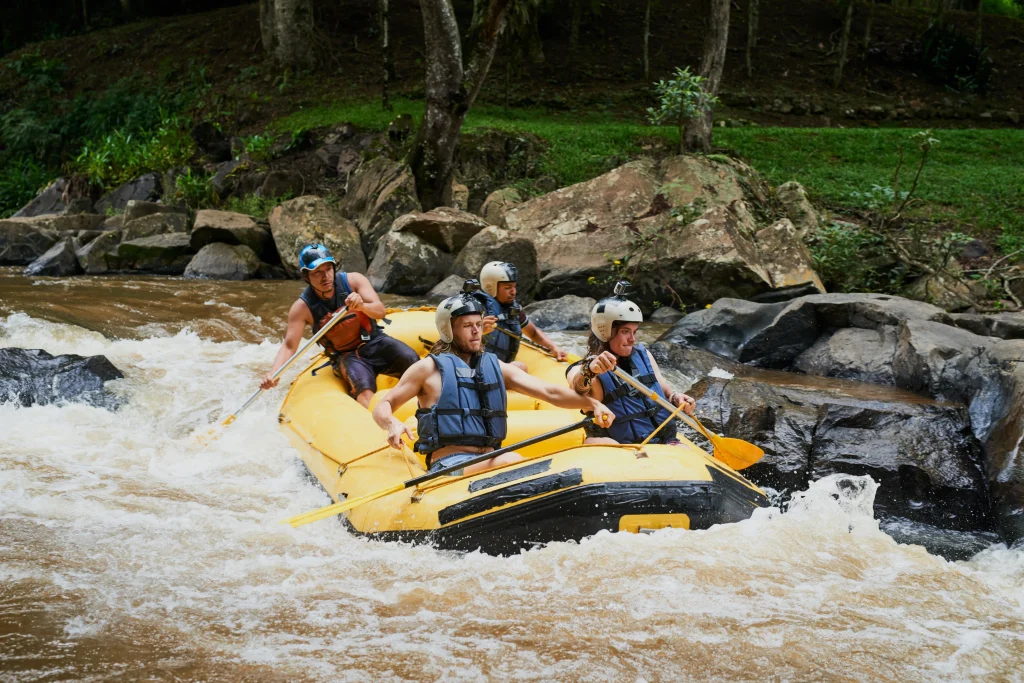 Rafting team paddling Ganga rapids during weekend adventure tour packages in Uttarakhand